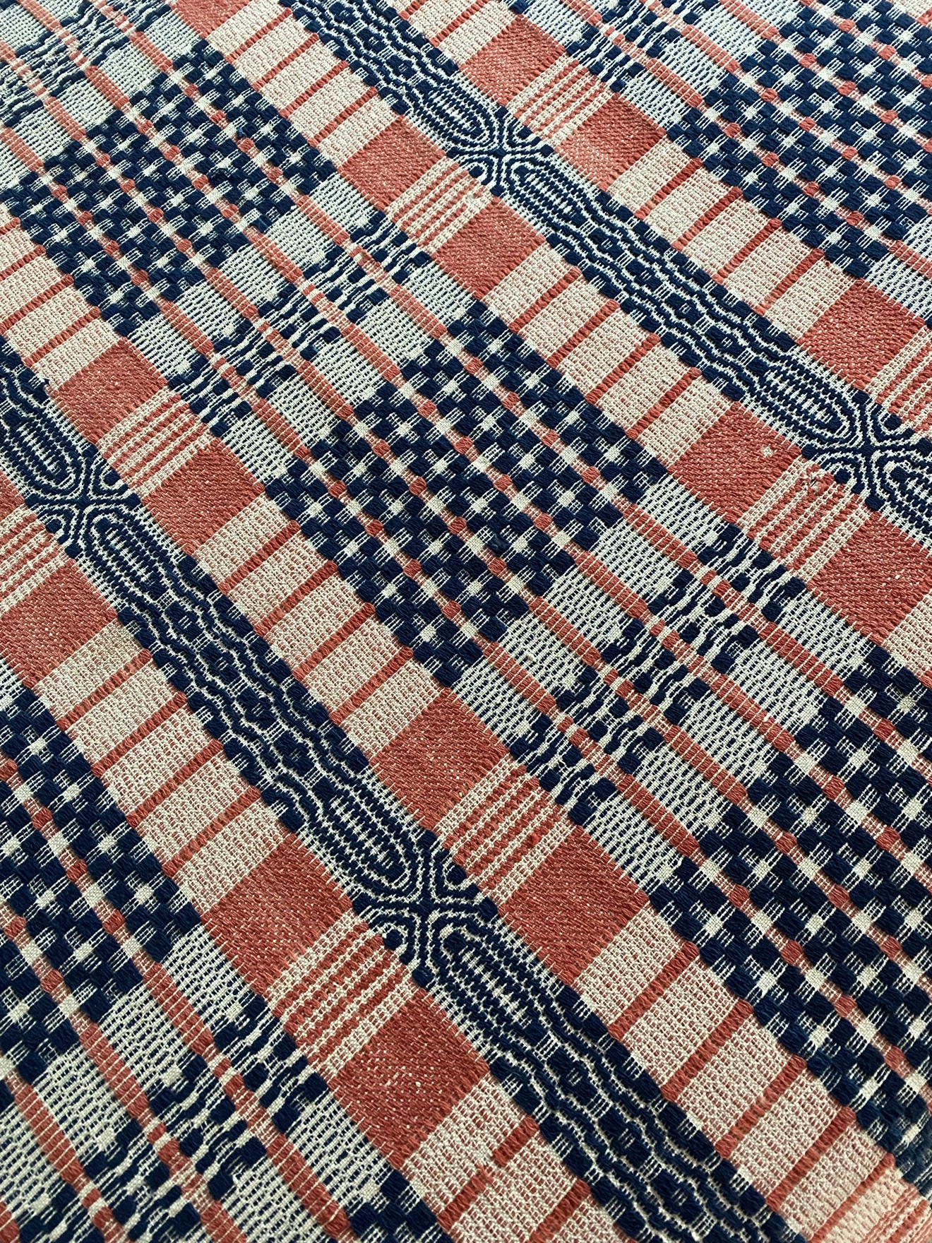 Close-up of a woven coverlet in red, blue and white overshot pattern